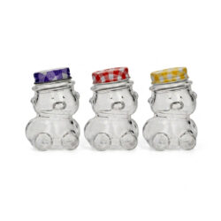 Borcan transparent din sticlă pentru miere, în formă de ursuleț, cu capac metalic colorat cu model în carouri și volum de 30 ml.